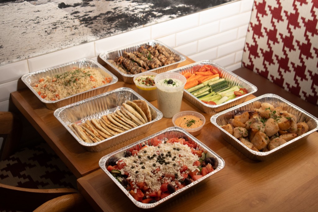 Office catering spread with souvlaki, salads, dips, and sides